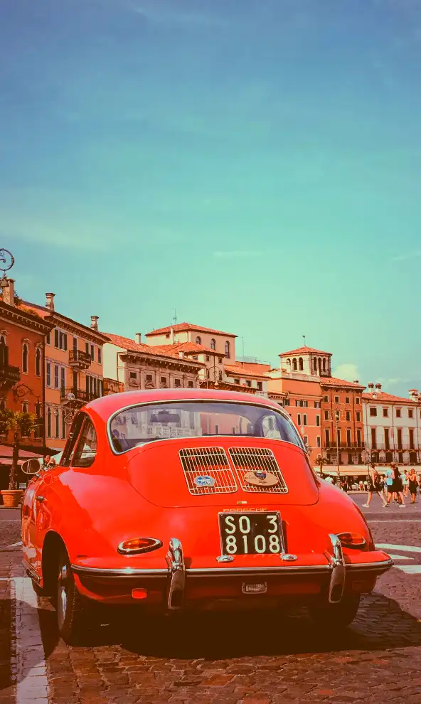 Vibrant red car against old buildings in Verona city, Italy, with CSS saturate filter set to 200%.