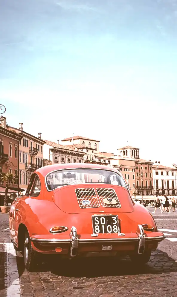 A photo of a red car with old buildings in the background, captured in Verona, Italy. The image has a CSS filter with 150% brightness, making it brighter than the original.