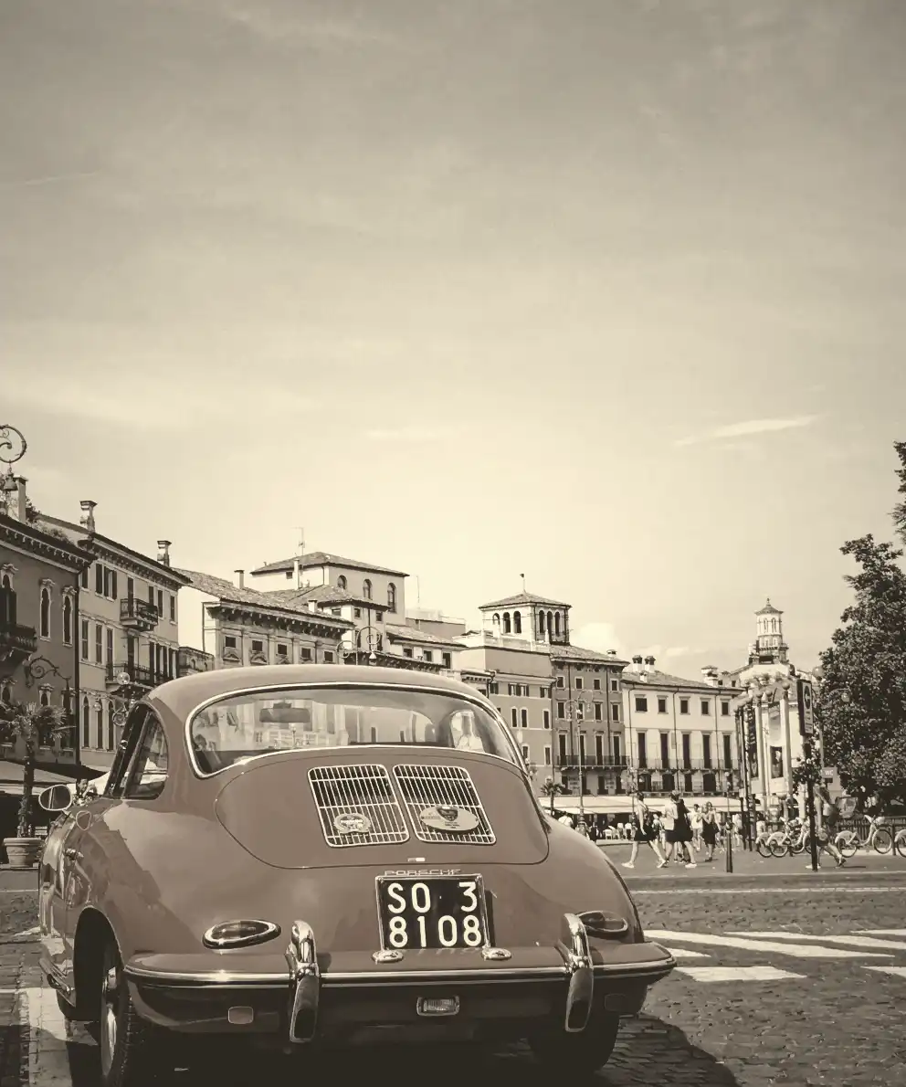 Red car against sepia and grayscale-filtered old buildings in Verona city, Italy