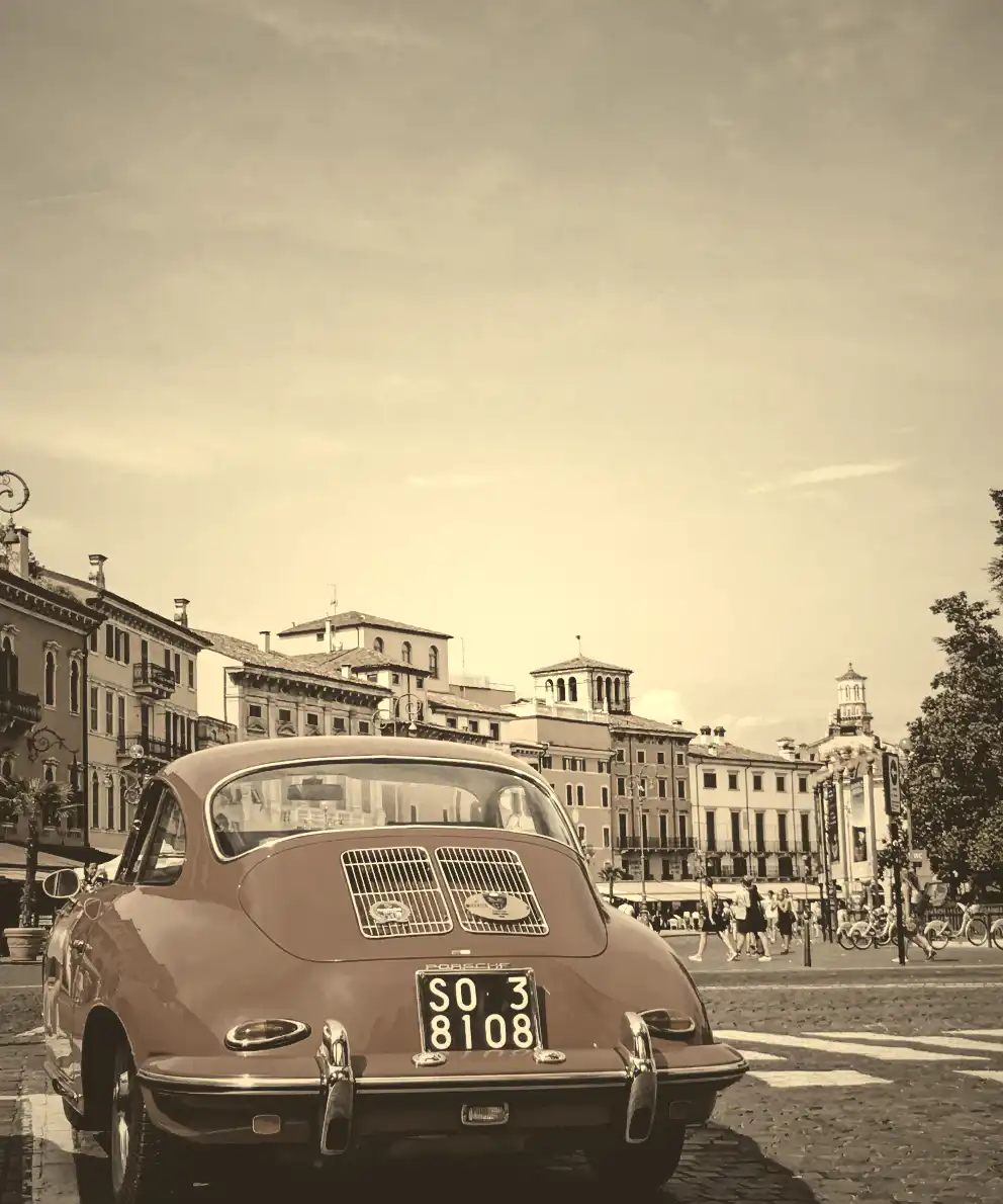 Red car with sepia-filtered old buildings in the background, captured in Verona city, Italy